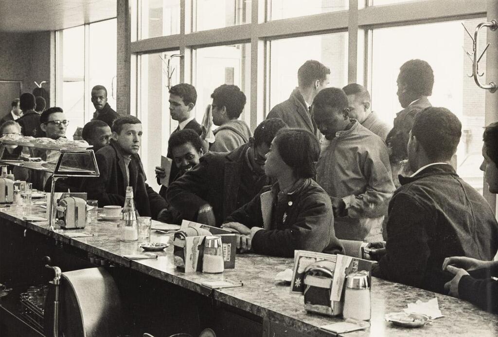 SNCC Staff SitIn Atlanta John Lewis behind Mendy Samstein the pastries Stokely Carmichael standing at right The Movement Together photographs Silver prints the first image measuring/x/ inchesx cm the sheet slightly larger and the second/x/ inchesx cm the sheetx inchesx cm the first with Lyons signature and extended title in pencil and his Bleak Beauty stamp with his initials and dates also in pencil on verso and the second with Lyons signature two credit stamps and additional notations in pencil on verso the first with a Gavin Browns enterprise label on frame verso