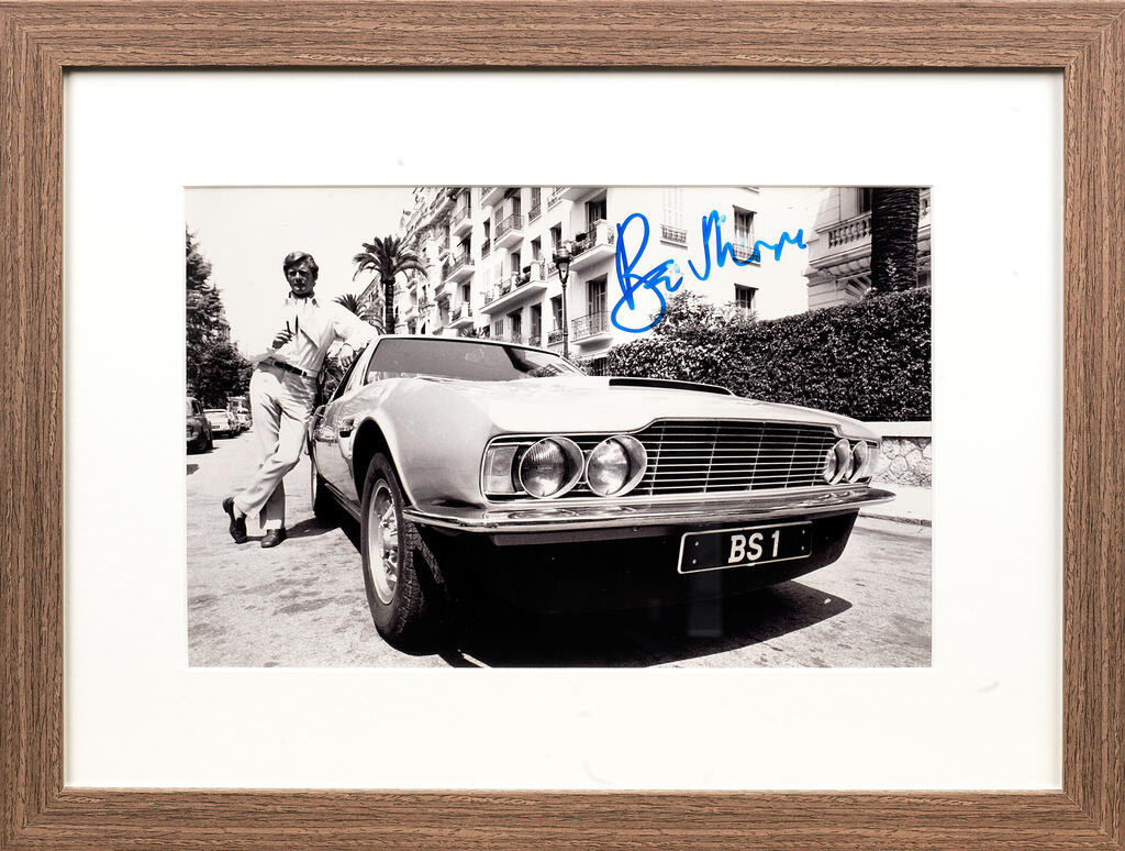 A framed Roger Moore signed image featuring the 'Persuaders' Aston Martin DBS,