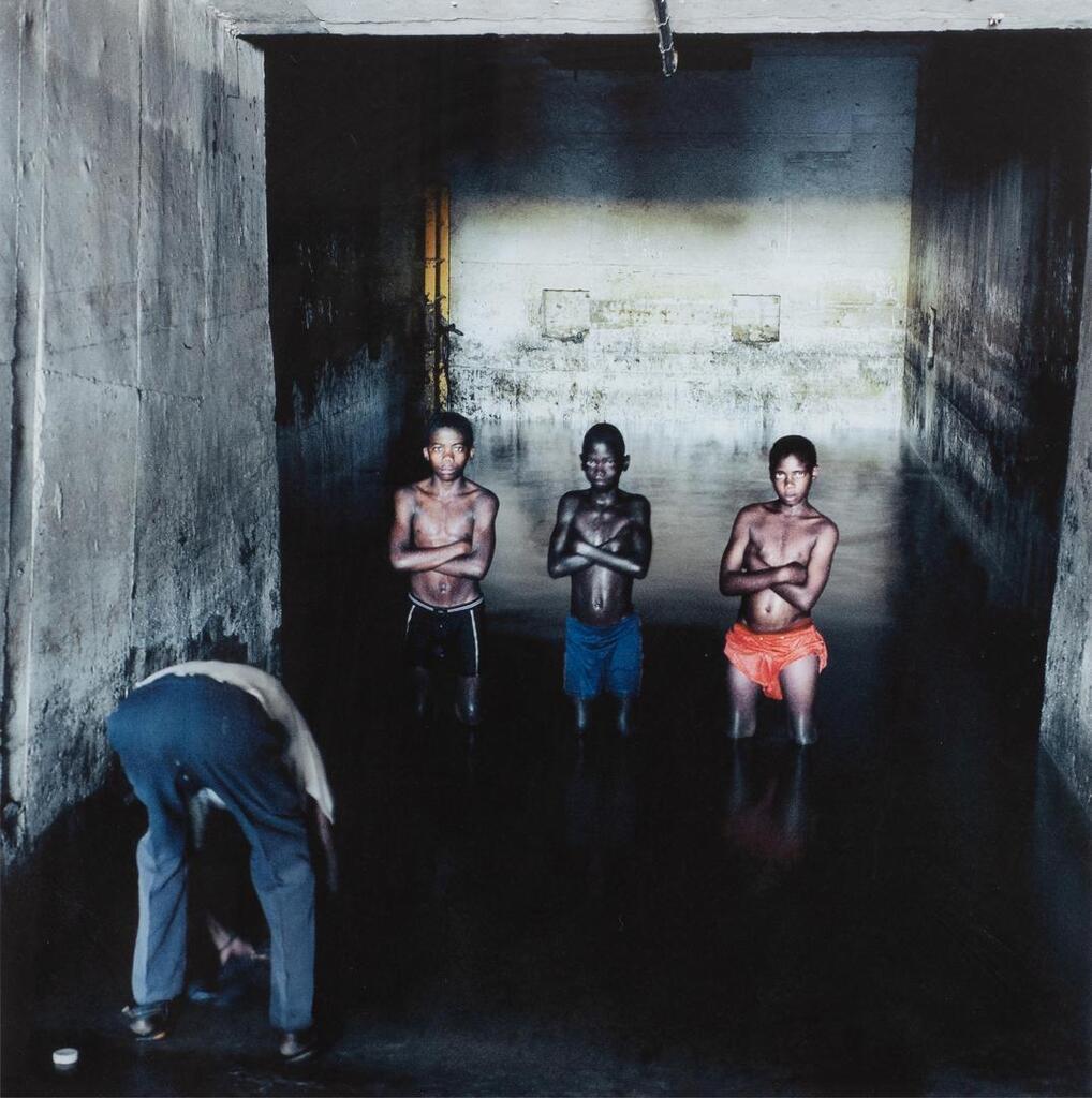 Fernando Augusto Luta washes his clothes while Augusto Mokinda (13), Ze Jano (12), and Ze Ndala (10) pose for a photograph in the water in which they swim in a mineshaft of the Pomfret Blue Asbestos Mine, Pomfret