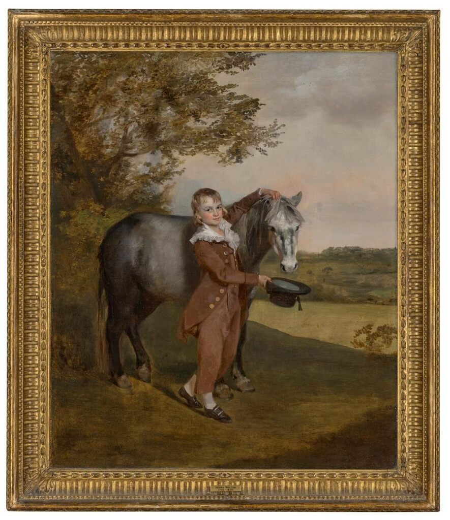 A young boy, small full-length, holding a pony and hat, in a landscape