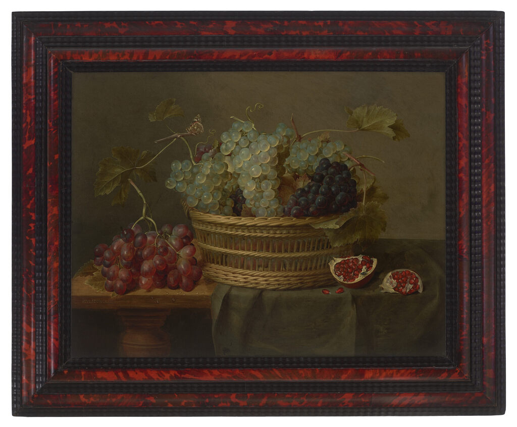 A basket of grapes and a pomegranate on a table