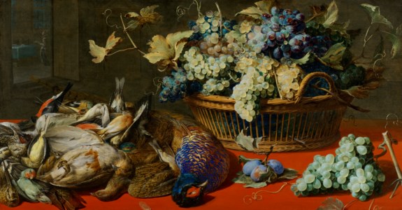 Game, plums and grapes on a red table cloth, next to a basket of grapes