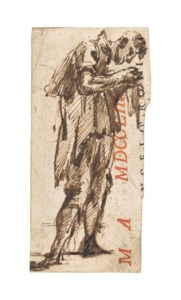 A standing man, seen in profile, examining a small object in his hands