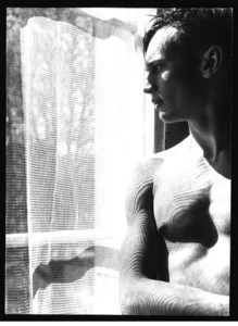 Young man behind drapes