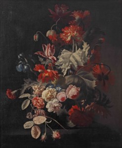Dalias, tulips, blue irises and other flowers in a glass vase on a stone ledge