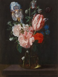 A tulip, roses, iris and other flowers in a glass vase on a stone plinth