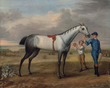 A grey racehorse held by a jockey, with a lad holding up a gold cup, at Newmarket