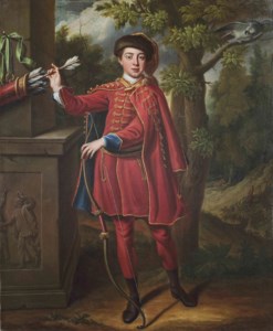 Portrait of a huntsman, full-length, in a red and gold embroidered cloak in a wooded landscape