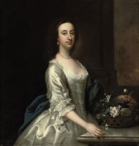 Portrait of a lady, three-quarter-length, in a lace-trimmed satin oyster dress with pearl ornaments and blue wrap, beside a ledge with a basket of flowers