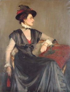 Portrait of Monica Boyd, three-quarter-length, seated in a black dress and red-feathered hat