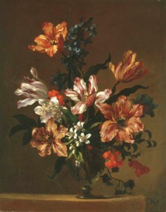 Parrot tulips and other flowers in a glass vase on a stone ledge