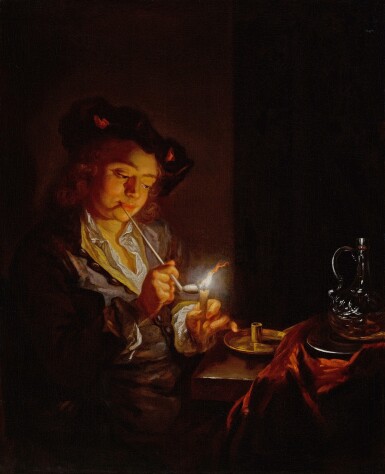 Candlelit interior with a young man seated at a table, lighting his pipe