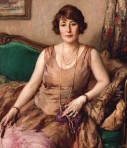 Portrait of a lady, seated on a sofa, wearing a pink dress and holding an ostrich feather fan