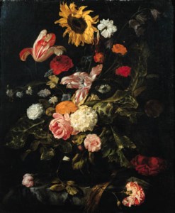 A sunflower, roses, parrot tulips, a carnation and other flowers in a glass vase on a partly draped marble table
