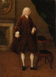 Portrait of a gentleman, full-length, in a brown coat and waistcoat, his left arm resting on a chair, his right hand holding a cane, in an interior