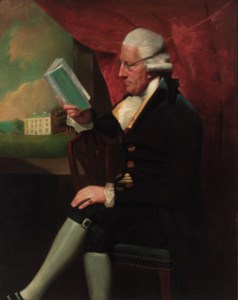Portrait of Edward Cotsford, seated three-quarter-length, in a dark brown jacket and breeches, holding a book by a window, a view to a country house beyond
