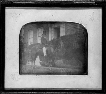 Gentleman with top hat on horseback outside his manor house circa early 1840s