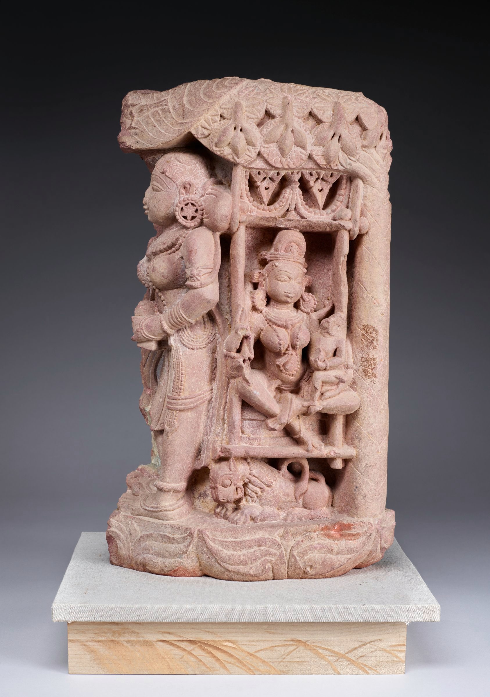 Jain Goddess Ambika with Child Seated on Her Husband who is Transformed into a Lion under a Fruiting Mango Tree with Yakshi Tree Goddess Holding a Bird Standing under a Tree Housing a Bird Architectural Fragment
