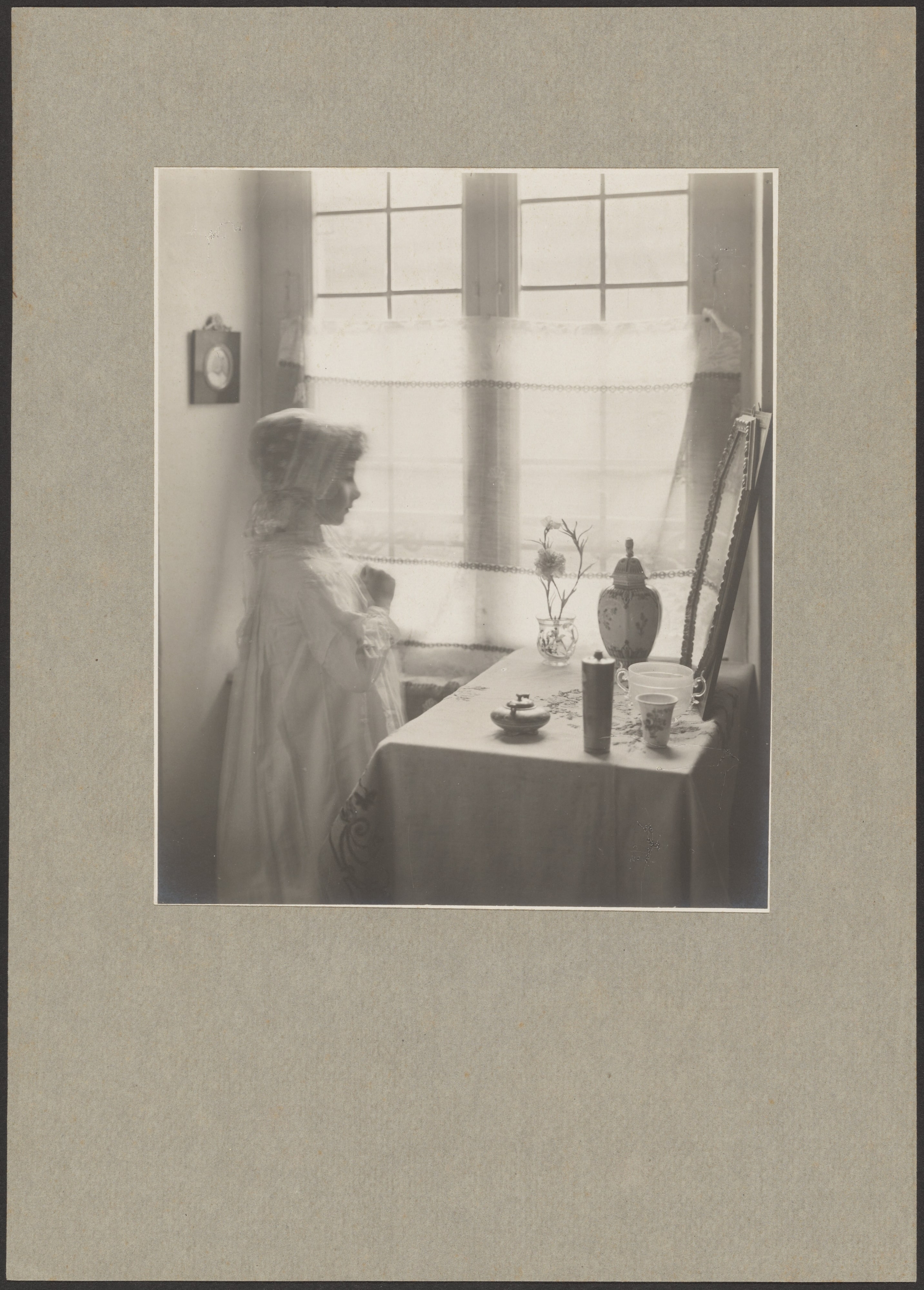 [Young Girl in Costume Looking Into a Mirror Resting on a Table]