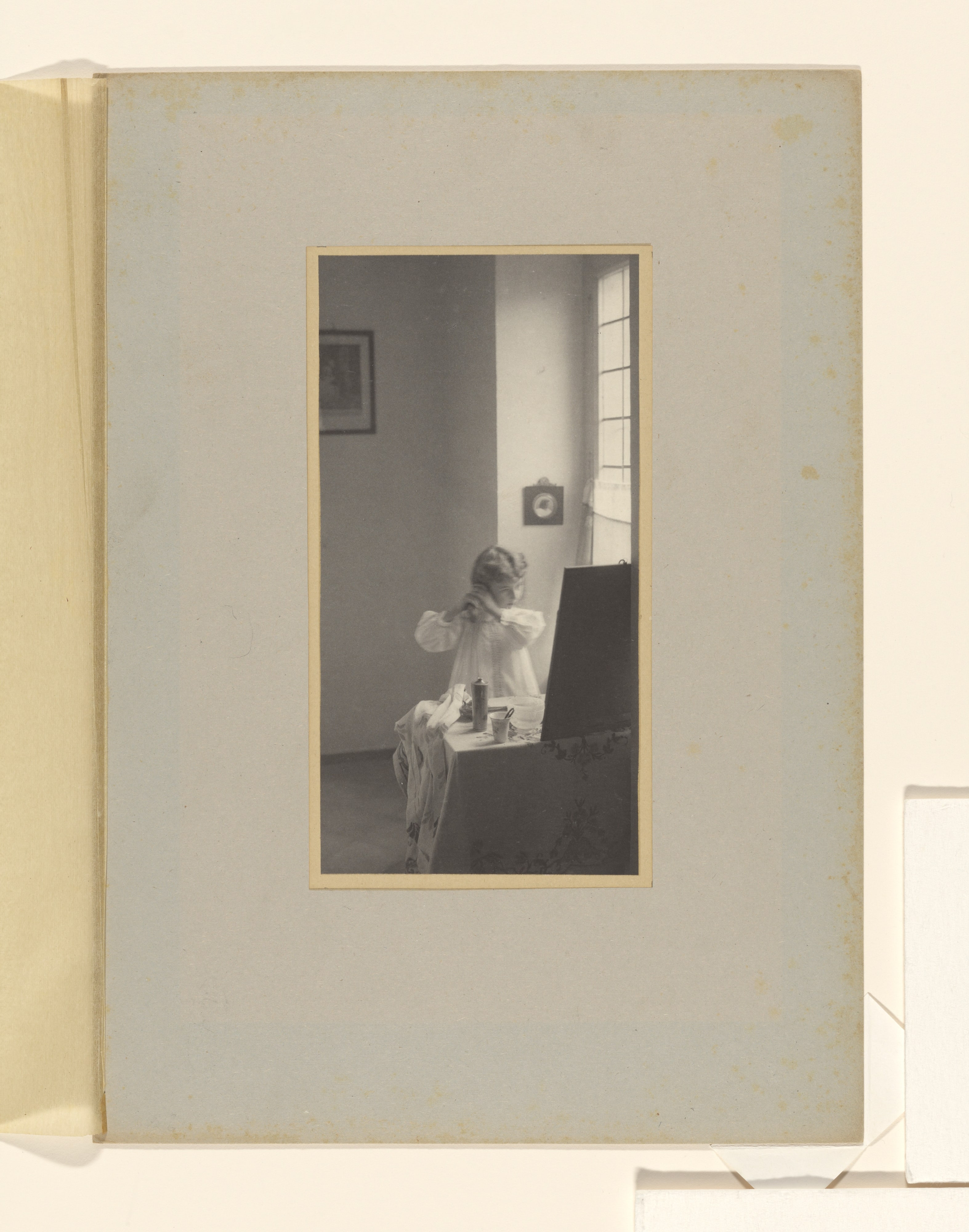 [Little Girl Fixing Her Hair Looking in a Mirror on a Small Table]