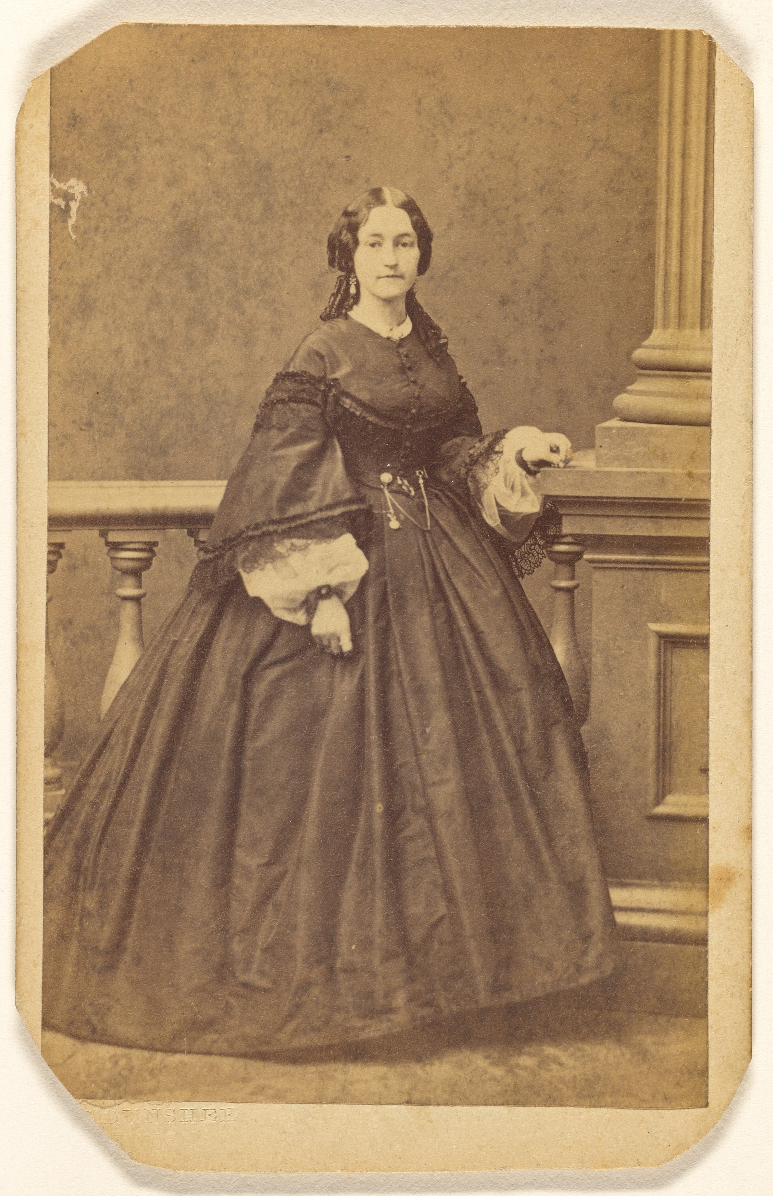 [Unidentified woman in long dress, standing]