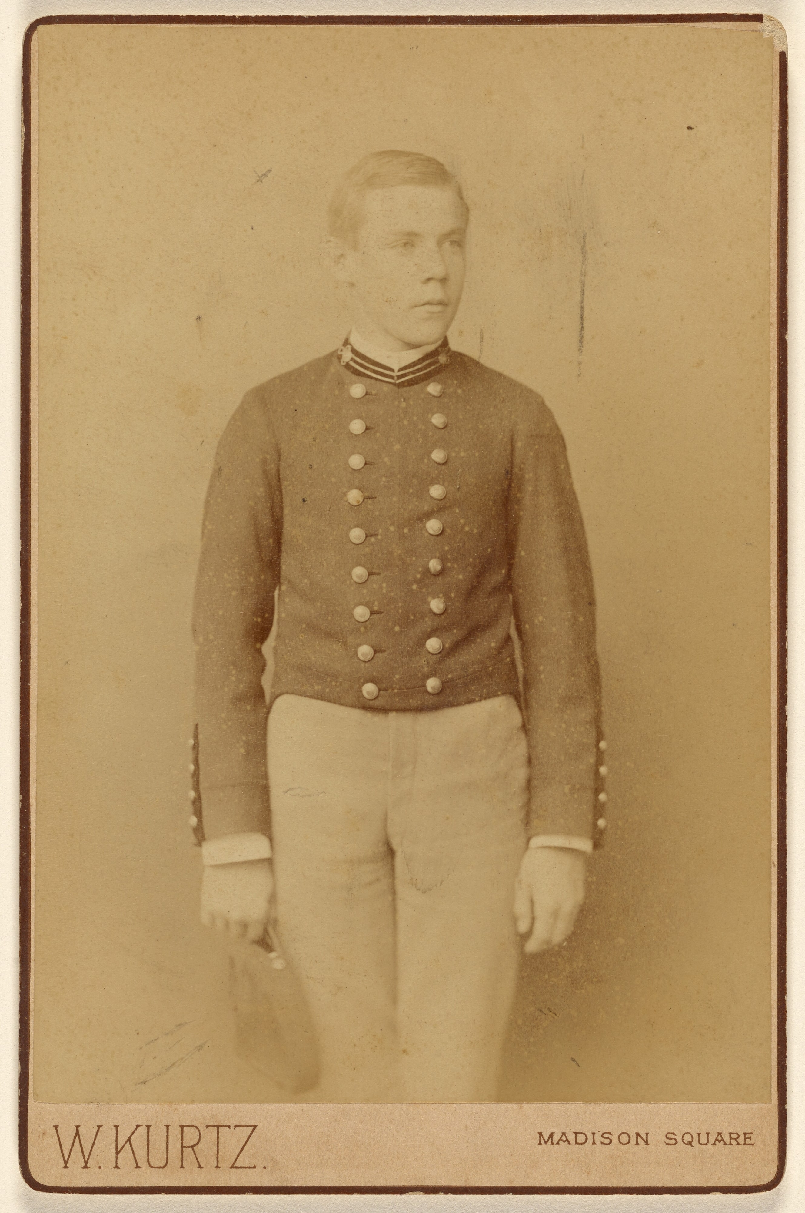 [Soldier standing, holding a cap]