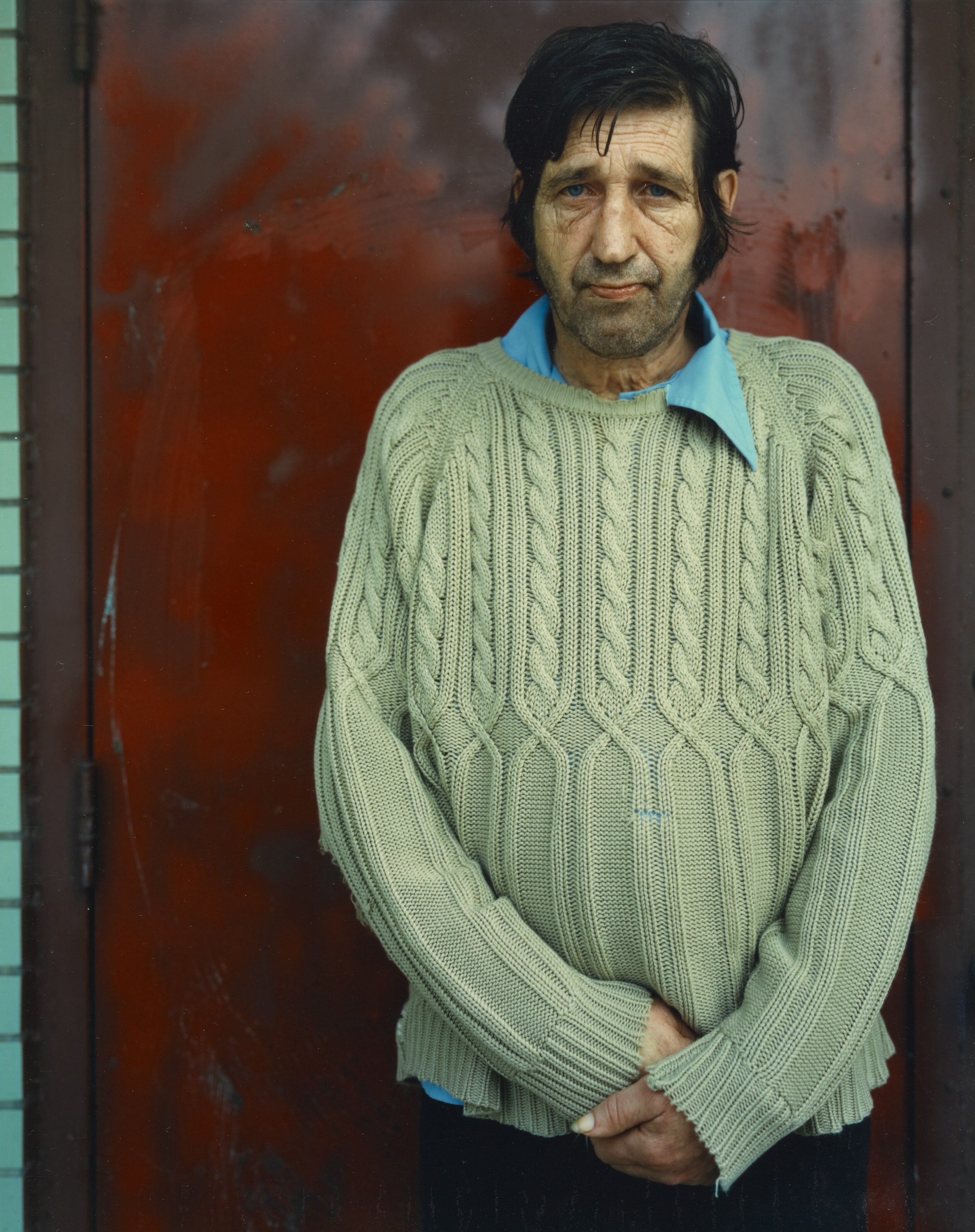 Binghamton, New York [man in sweater against red wall]