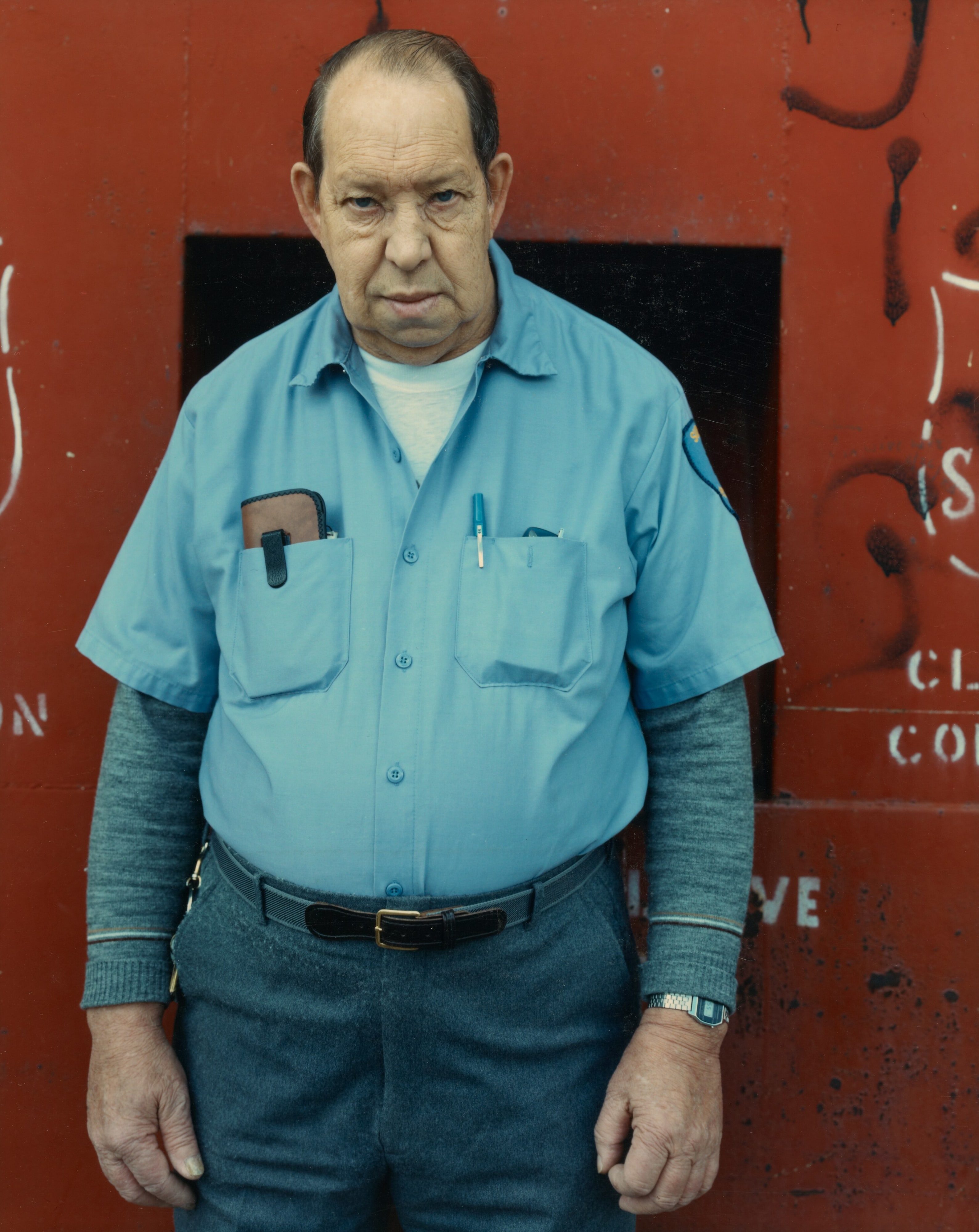 Binghamton, New York [man in blue shirt against red wall]