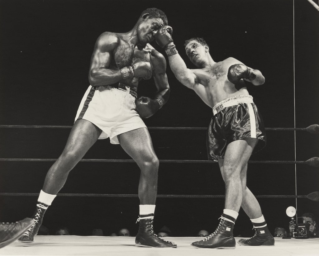 Champion Rocky Marciano, his eye cut, flattens challenger Ezzard Charles' nose with crushing right uppercut in sixth at stadium