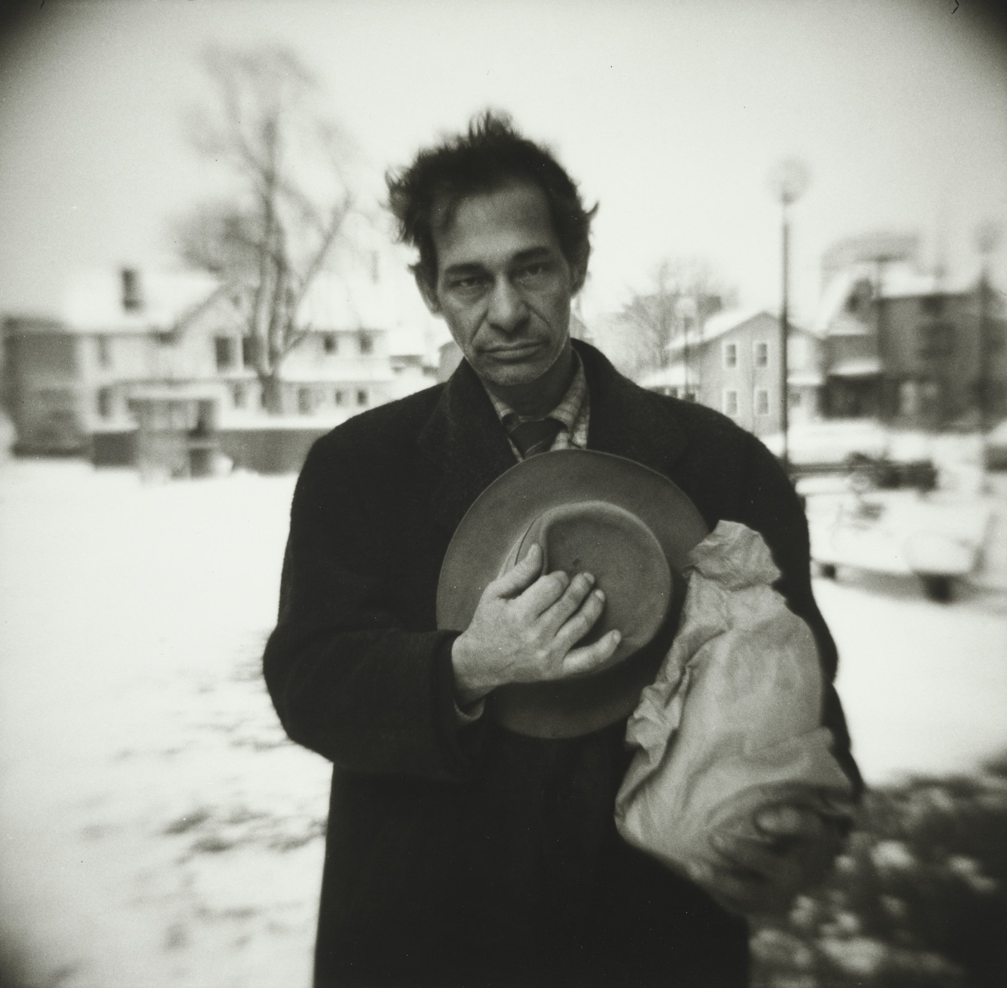 Man Holding Hat and Wine Bottles