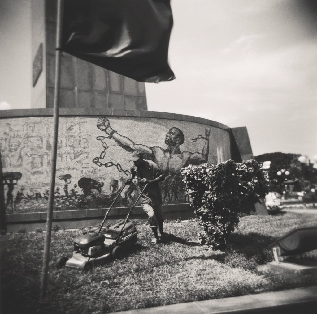 Man maintaining the lawn of the Monumento de Agostinho Neto from the series Terreno Ocupado