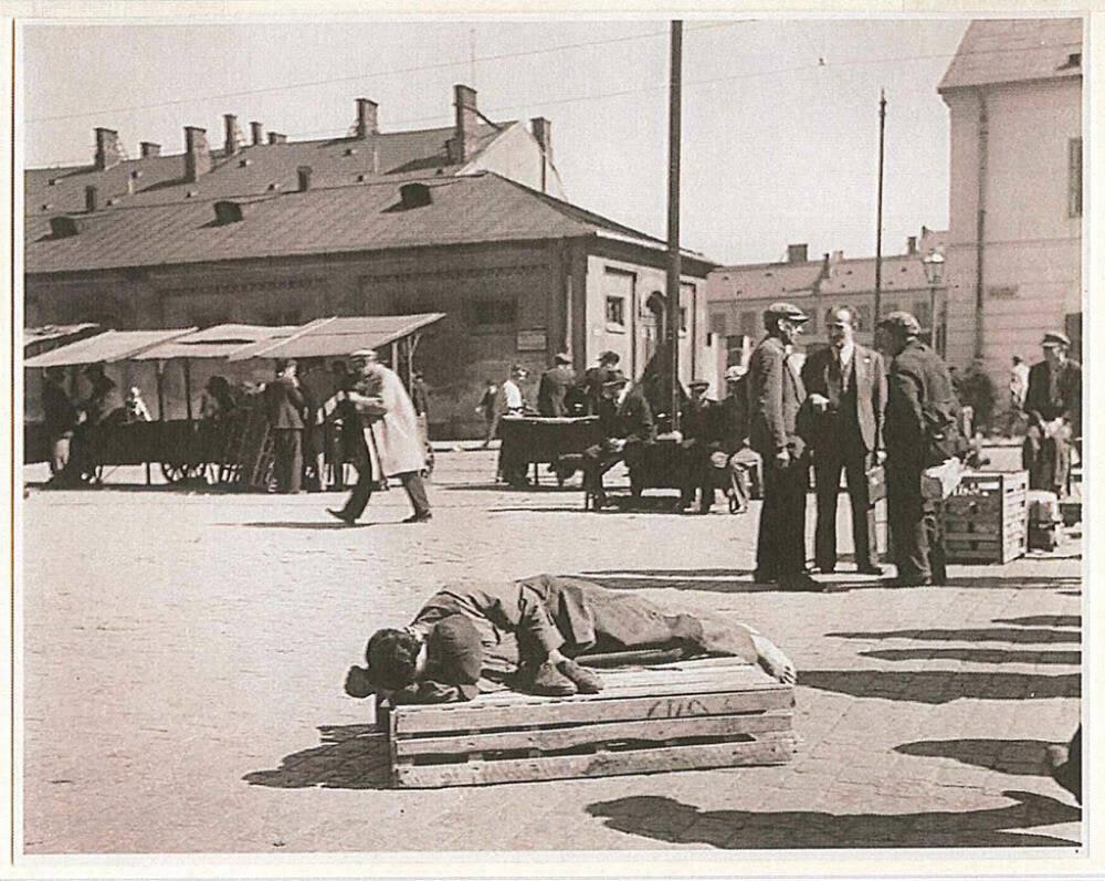 A porter asleep on top of his carrying box. He is holding on to his most valuable possession: his shoes, Warsaw