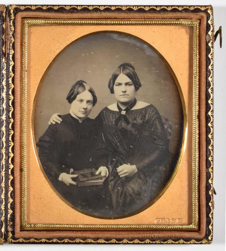 [Two Women, One Holding Book]