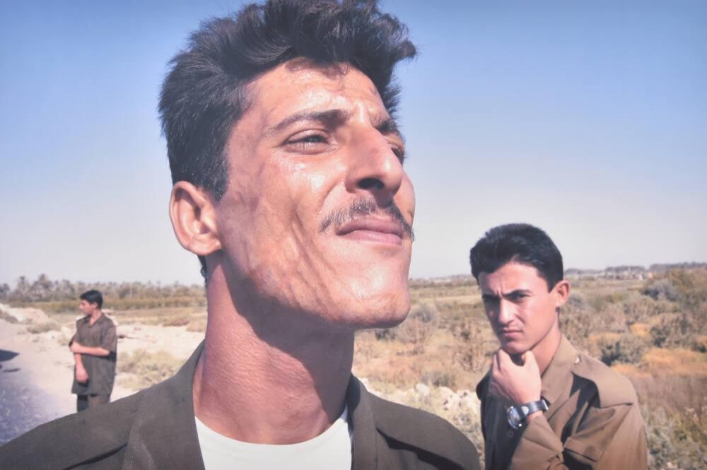 An Iraqi policeman, who says he was tortured by Hussein's forces, stops traffic after an attack against U.S. soldiers, Ar Ramadi