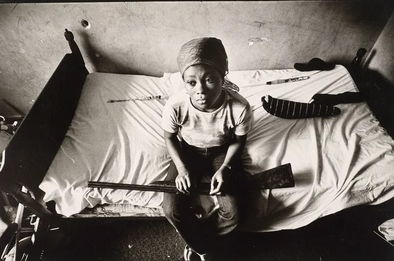 Female resident sitting with only a nonworking rifle for protection, "Pink Palace" housing project, San Francisco, California