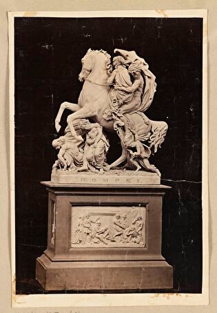Photo of Wiktor Brodzki’s sculpture “Flight from Pompeii” (Fuga Pompei). View of a sculpture on a pedestal from the side with the inscription “POMPEI”