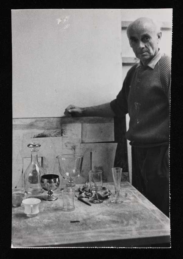 ‘Photograph of Ben Nicholson standing next to table with glasses on it