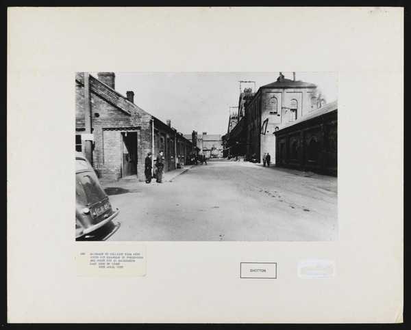 ‘429. Approach to colliery yard with South Pit headgear in foreground and North Pit in background. Lamp room on right. 12th April 1957’