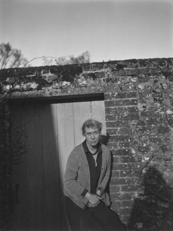 ‘Black and white negative of Vanessa Bell looking at the camera, standing in front the garden door at Charleston, Firle, Sussex