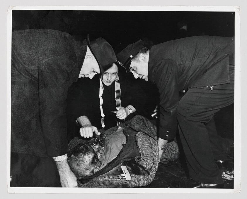 A passing priest gives the injured man the last rites of the Church