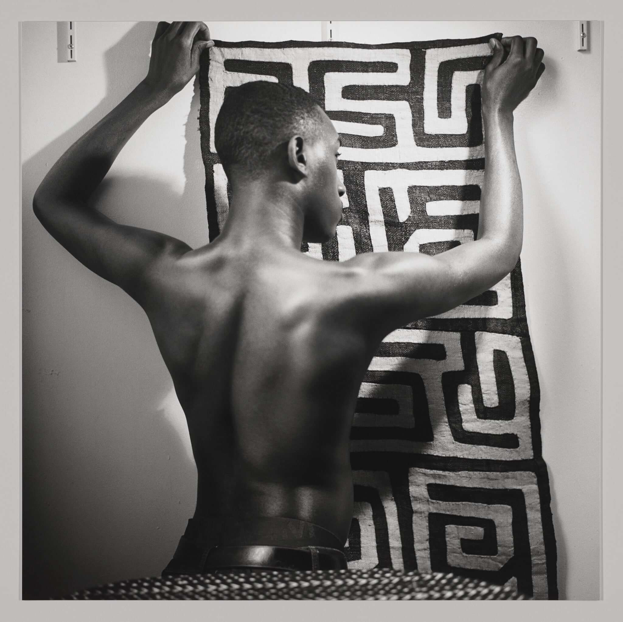 Young man holding up Kuba cloth