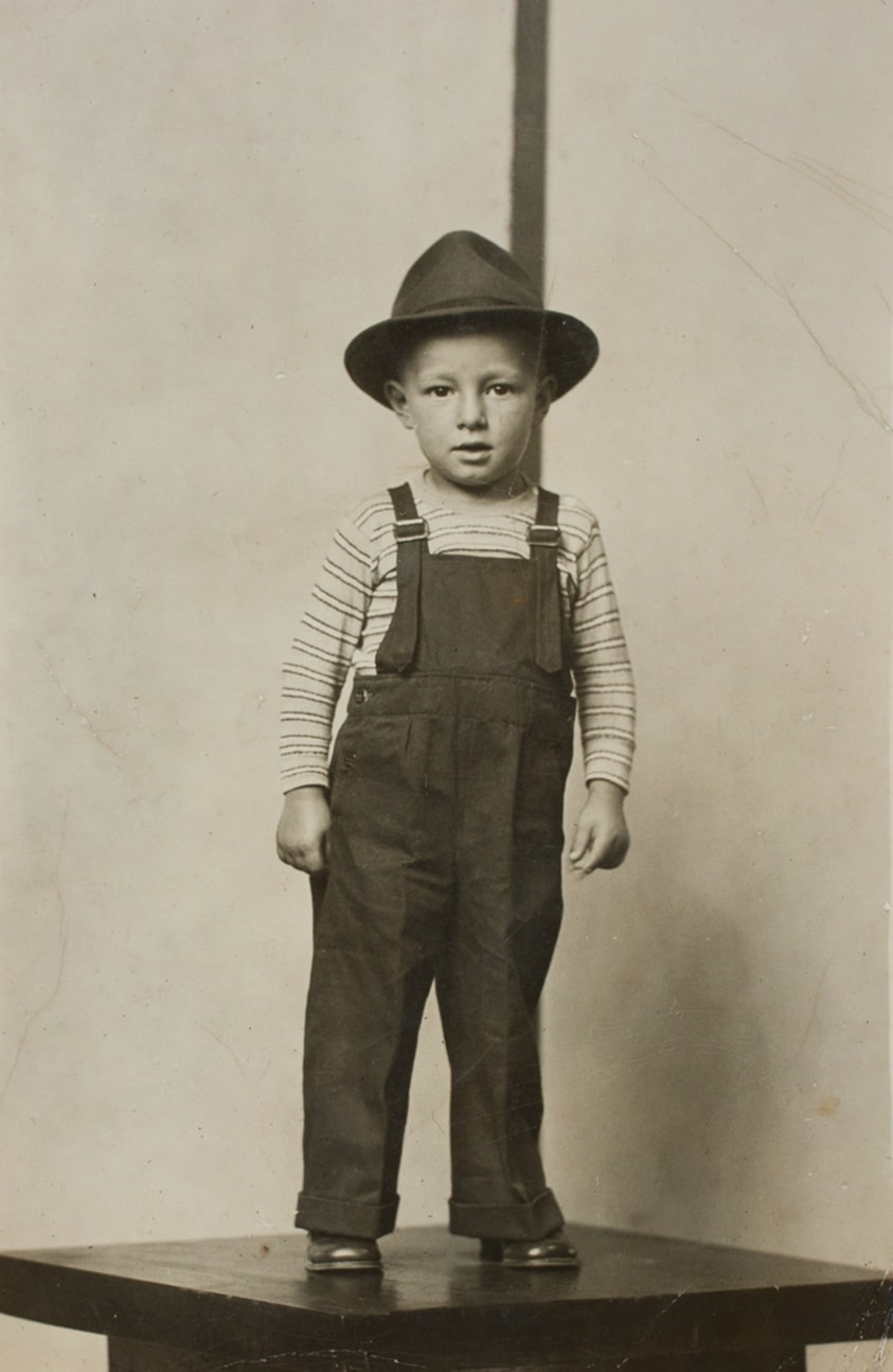 Boy in Hat and Overalls Standing on Table
