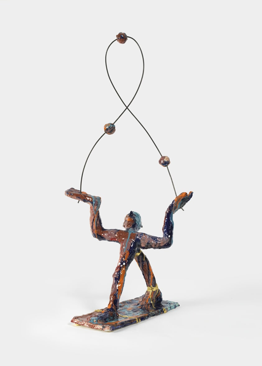 man standing juggling three balls by first light of day