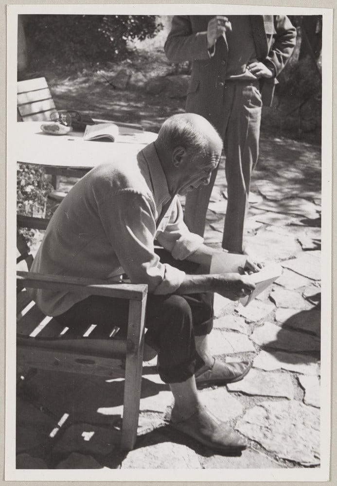 Pablo Picasso assis lisant une lettre sur la terrasse de La Galloise, Vallauris, en 1952
