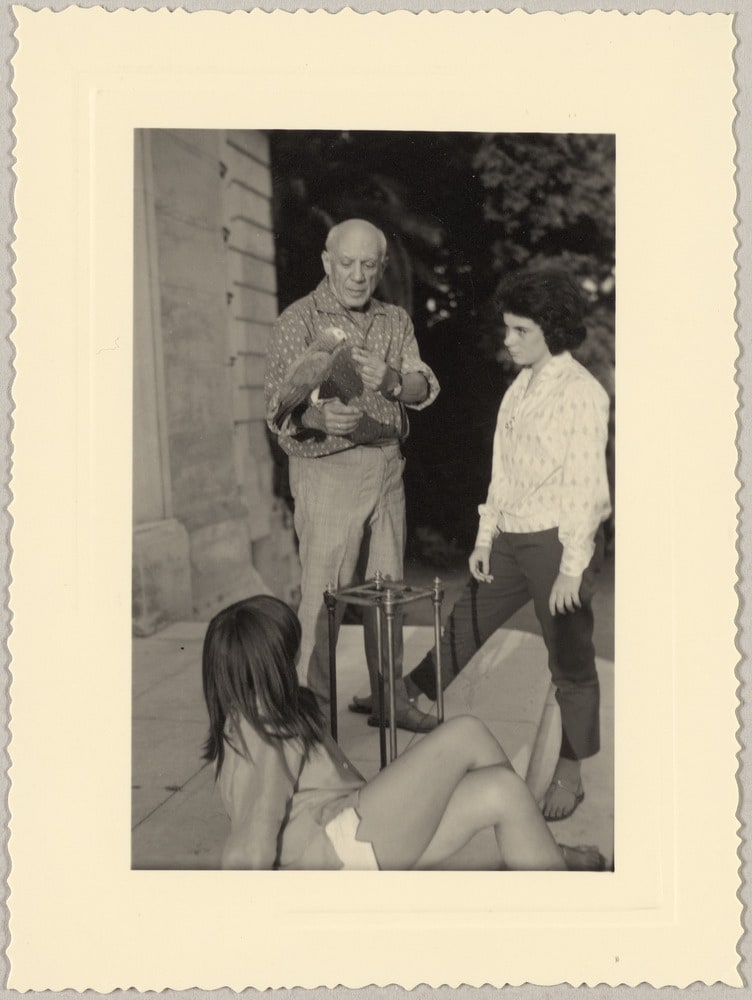 Catherine Hutin regardant un perroquet posé sur la main de Pablo Picasso avec Paloma assise sur les marches du perron de La Californie, Cannes, en [1960]