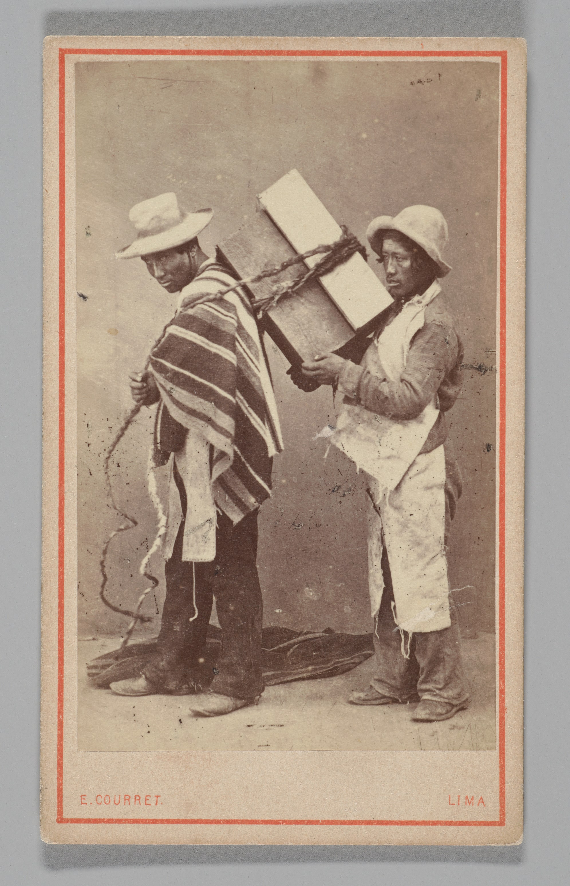 [Studio Portrait: Two Men, one with Box Tied to his Back, Lima]