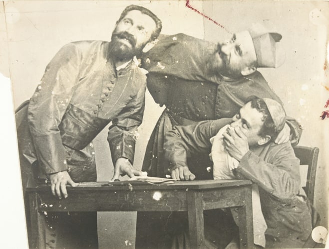 Trois hommes, vêtus de costumes sacerdotaux, autour d'une table