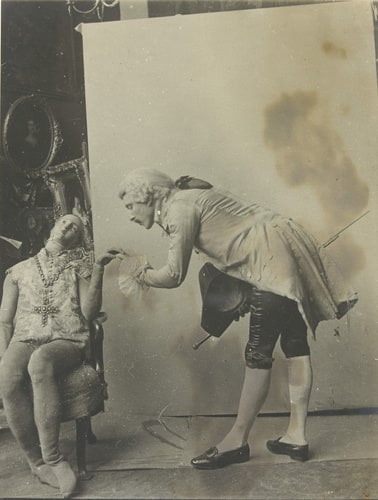 Homme déguisé en courtisan de la cour de Louis XV penché sur un mannequin féminin en bois et chiffon pour lui faire un baise-main